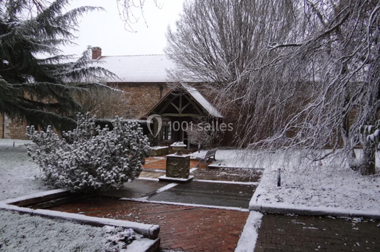 Location salle La Villeneuve-en-Chevrie (Yvelines) - La Grange des Mollières #23 Jardin enneigé avec allées en briques, arbres givrés et bâtiment en pierre au fond.