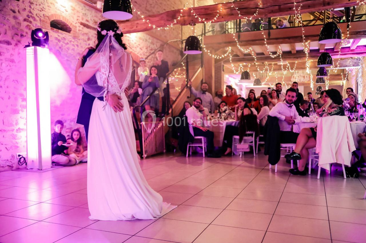 Location salle La Villeneuve-en-Chevrie (Yvelines) - La Grange des Mollières #5 Un couple de mariés danse sous des lumières féeriques, entouré d'invités dans une salle décorée.