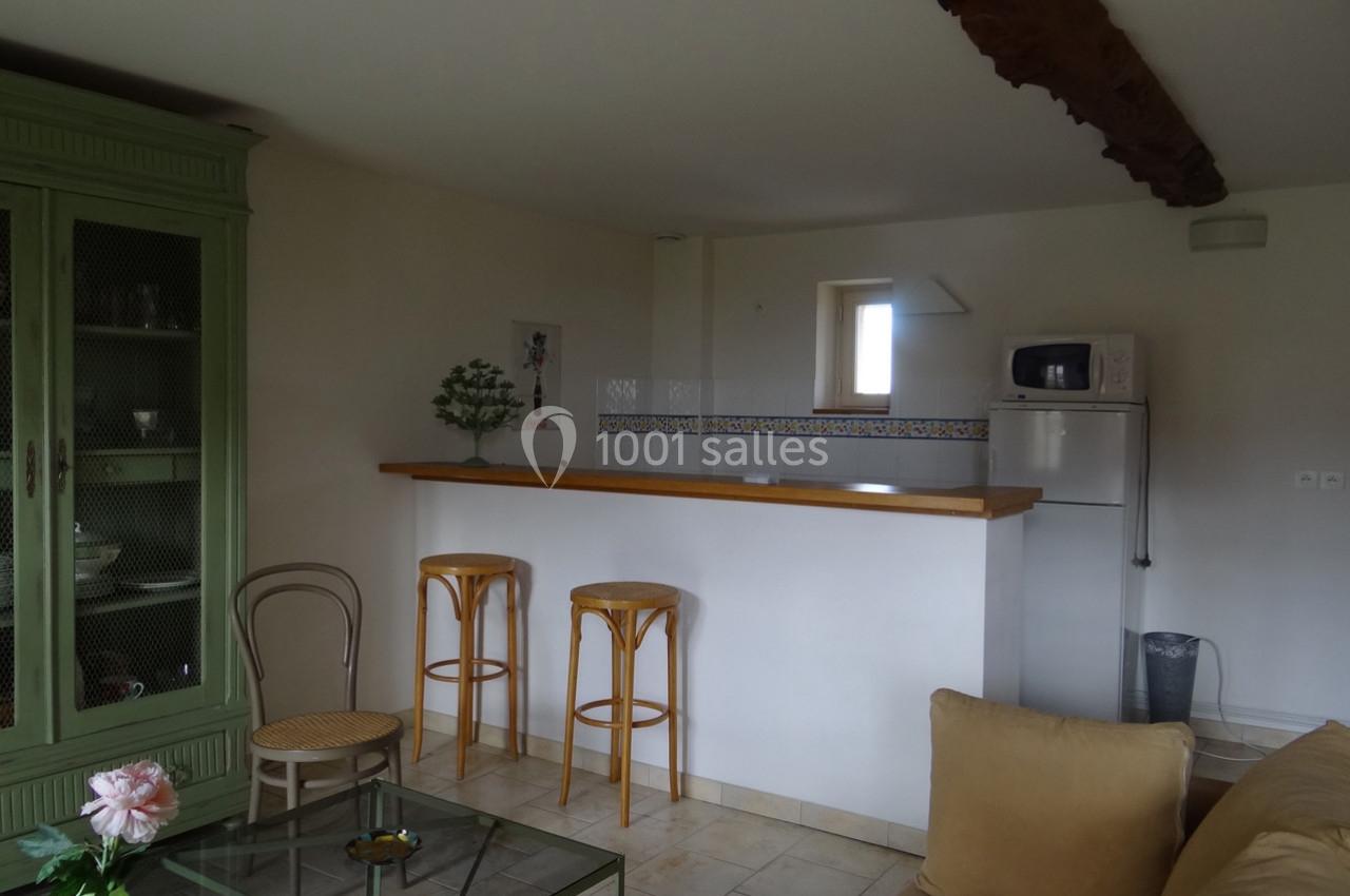 Location salle La Villeneuve-en-Chevrie (Yvelines) - La Grange des Mollières #49 Cuisine ouverte avec un bar en bois, deux tabourets, un réfrigérateur, un micro-ondes et un meuble vert dans un salon…