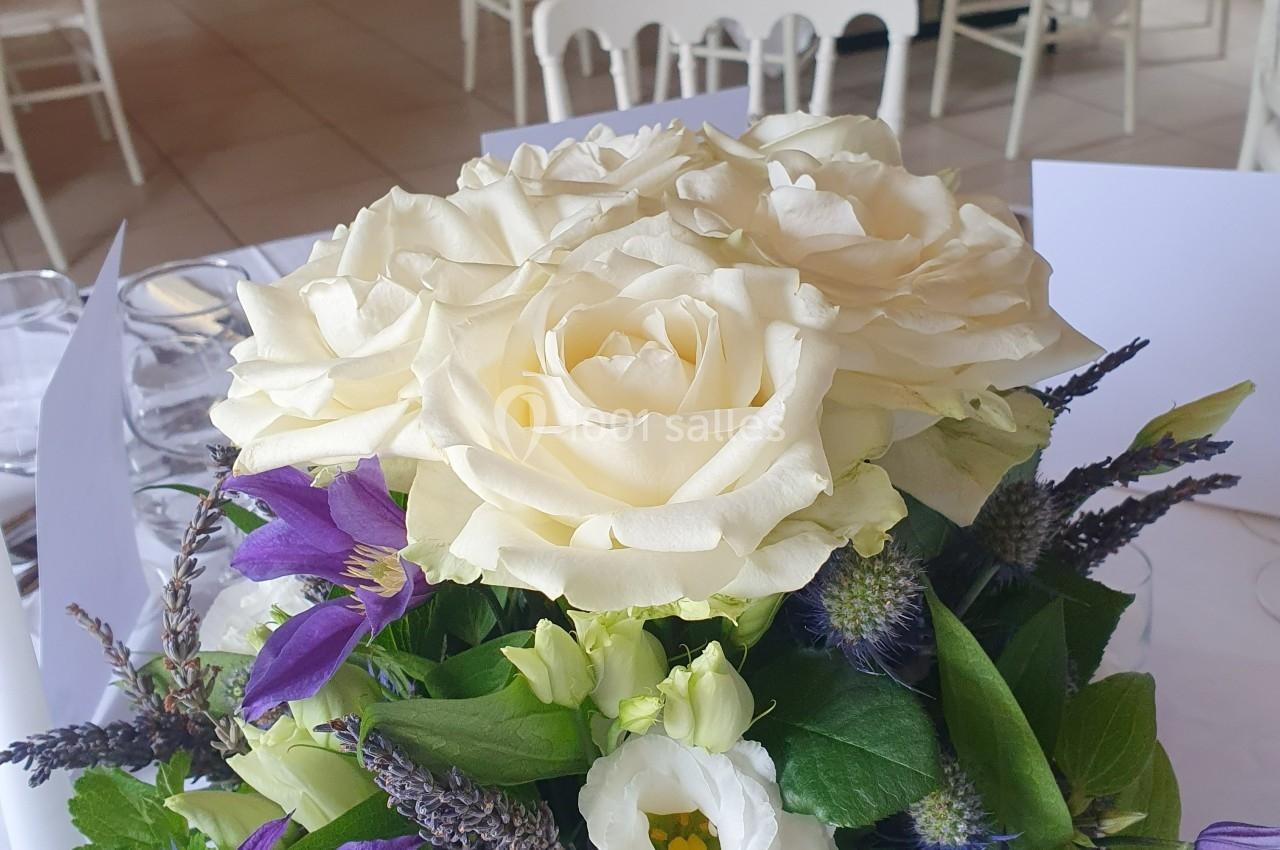 Location salle La Villeneuve-en-Chevrie (Yvelines) - La Grange des Mollières #45 Bouquet de fleurs comprenant des roses blanches, des lavandes et des feuillages, posé sur une table dressée.