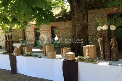 Miniature Location salle Haute-Goulaine (Loire-Atlantique) - La Cour des Montys #18 Cour extérieure éclairée en soirée, avec un grand arbre central, des tables, des palettes en bois et des invités debout.