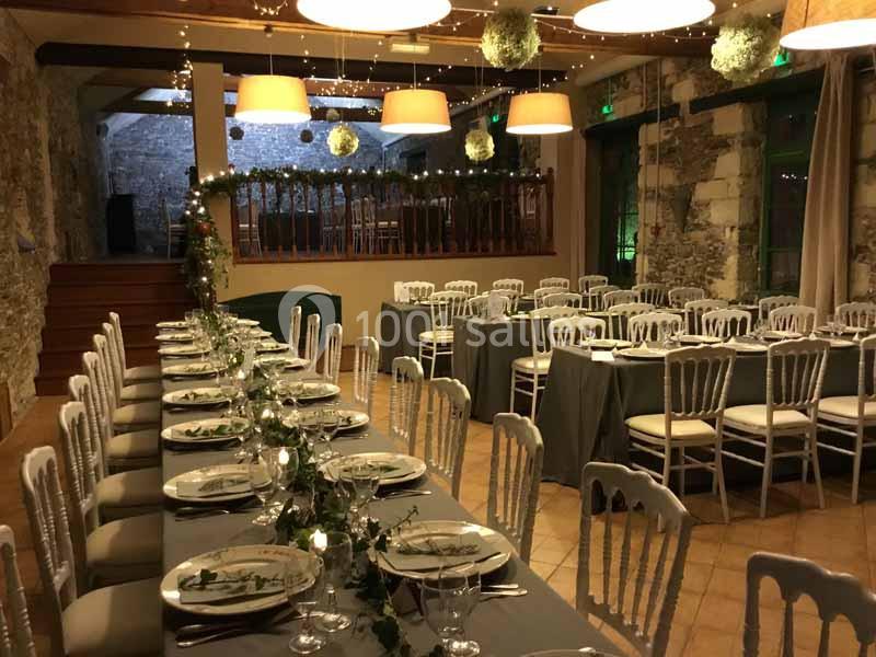 Location salle Haute-Goulaine (Loire-Atlantique) - La Cour des Montys #5 Salle de réception décorée avec des tables alignées, nappes grises, chaises blanches et guirlandes lumineuses.