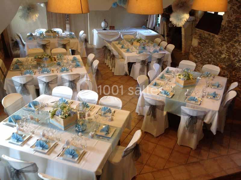 Location salle Haute-Goulaine (Loire-Atlantique) - La Cour des Montys #11 Salle de réception décorée avec des tables dressées, nappes blanches, serviettes bleues et centres de table fleuris.