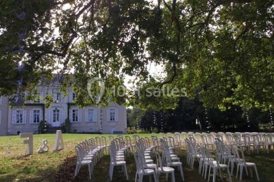 Miniature Location salle Haute-Goulaine (Loire-Atlantique) - La Cour des Montys #21 Cour extérieure éclairée en soirée, avec un grand arbre central, des tables, des palettes en bois et des invités debout.