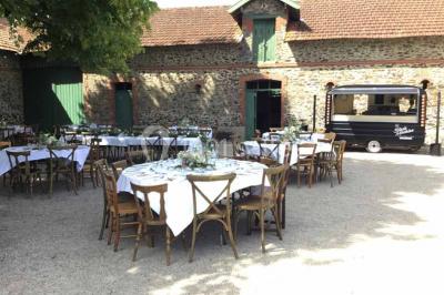 Miniature Location salle Haute-Goulaine (Loire-Atlantique) - La Cour des Montys #23 Cour extérieure éclairée en soirée, avec un grand arbre central, des tables, des palettes en bois et des invités debout.