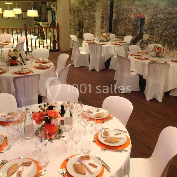 Location salle Haute-Goulaine (Loire-Atlantique) - La Cour des Montys #9 Salle de réception avec tables rondes dressées, nappes blanches, décorations orange et centres de table fleuris.
