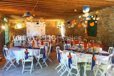 Miniature Location salle Haute-Goulaine (Loire-Atlantique) - La Cour des Montys #12 Cour extérieure éclairée en soirée, avec un grand arbre central, des tables, des palettes en bois et des invités debout.