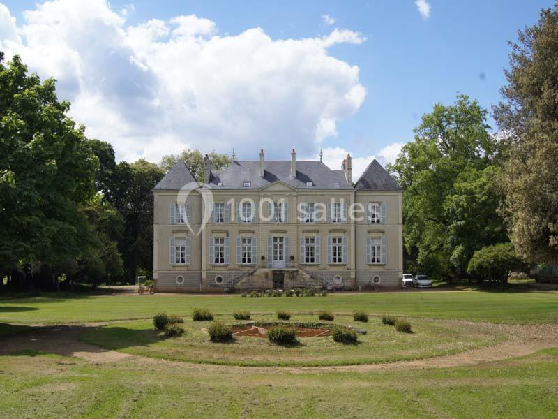 Location salle Haute-Goulaine (Loire-Atlantique) - La Cour des Montys #2 Façade d'un château en pierre entouré de pelouses et d'arbres sous un ciel partiellement nuageux.