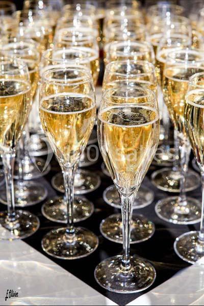 Rangées de flûtes remplies de champagne doré disposées sur une table.