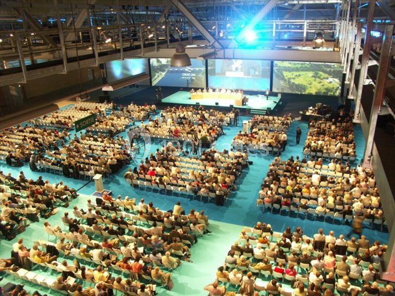 Location salle Nantes (Loire-Atlantique) - Exponantes Le Parc #4 Salle de conférence bondée avec des participants assis, une scène principale et plusieurs écrans de projection.