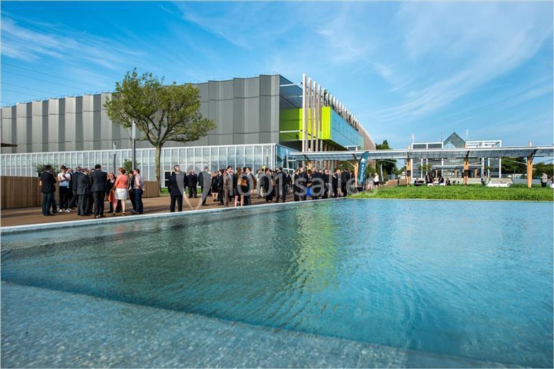 Location salle Nantes (Loire-Atlantique) - Exponantes Le Parc #5 Groupe de personnes rassemblées près d'un bâtiment moderne avec une façade colorée, devant un bassin d'eau.
