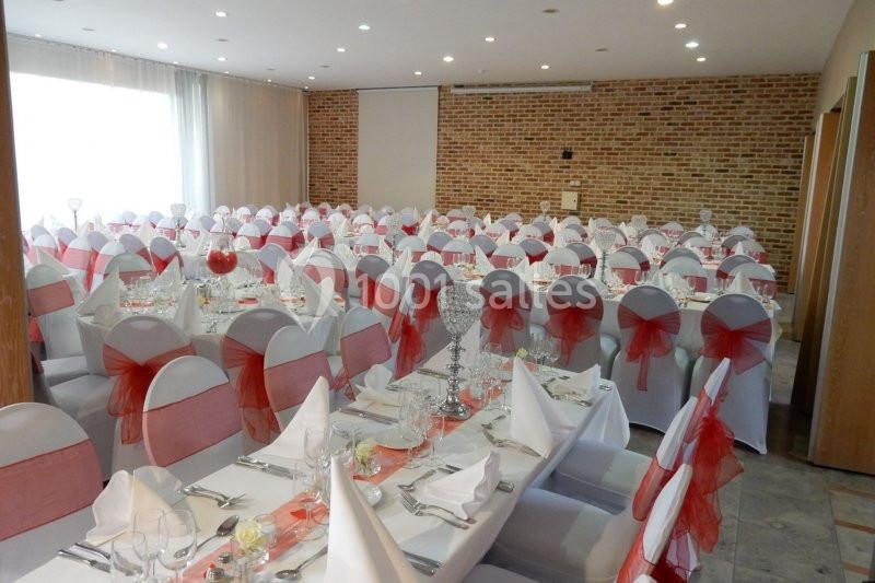 Location salle Donceel (Liège) - Château de Limont #6 Salle de réception décorée avec des nappes blanches et des chaises ornées de nœuds rouges, tables dressées pour un événement.