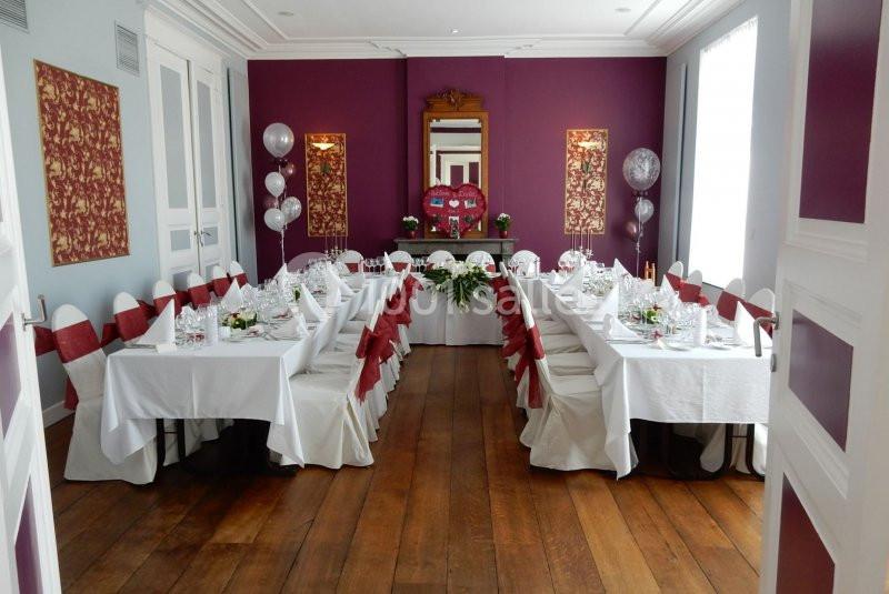 Location salle Donceel (Liège) - Château de Limont #5 Salle décorée pour un événement avec tables dressées, nappes blanches, chaises ornées de rubans rouges et ballons argentés.