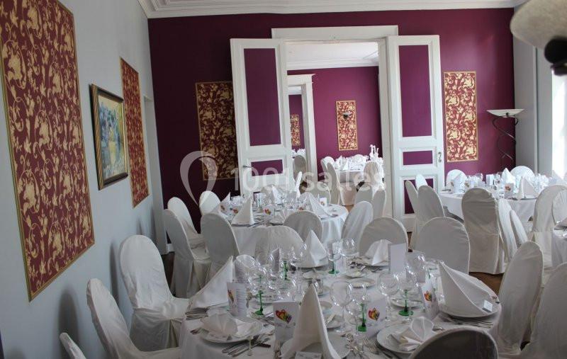 Location salle Donceel (Liège) - Château de Limont #13 Salle de réception élégante avec tables dressées, nappes blanches et décorations murales rouges à motifs dorés.