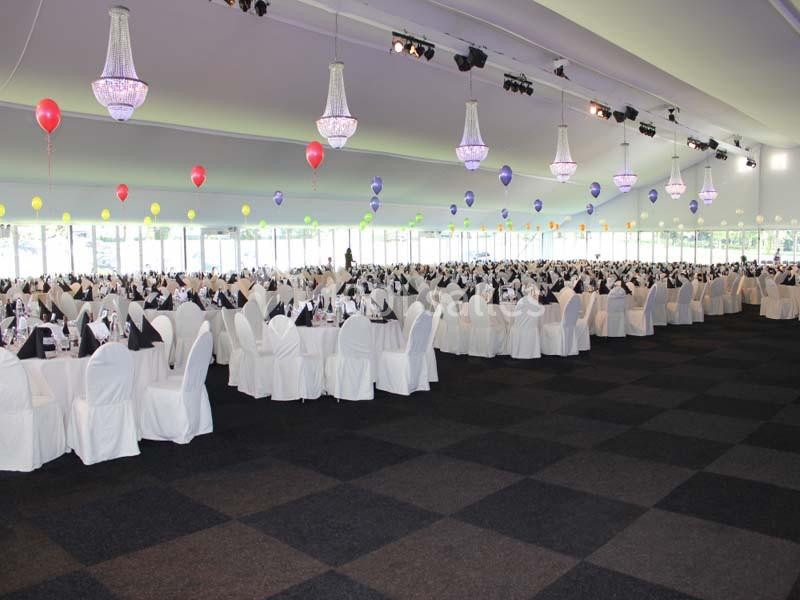 Location salle Donceel (Liège) - Château de Limont #12 Salle de réception spacieuse avec des tables dressées, des chaises blanches et des ballons colorés suspendus.