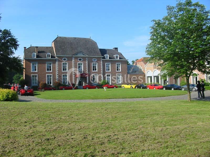 Location salle Donceel (Liège) - Château de Limont #17 Façade d'un manoir en briques rouges entouré de pelouses, avec des voitures garées devant sur une allée pavée.