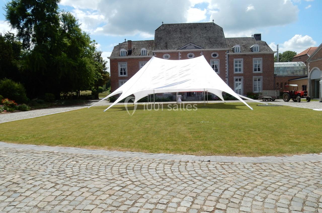 Location salle Donceel (Liège) - Château de Limont #11 Tente blanche installée sur une pelouse devant un bâtiment en briques rouges avec des fenêtres à volets blancs.