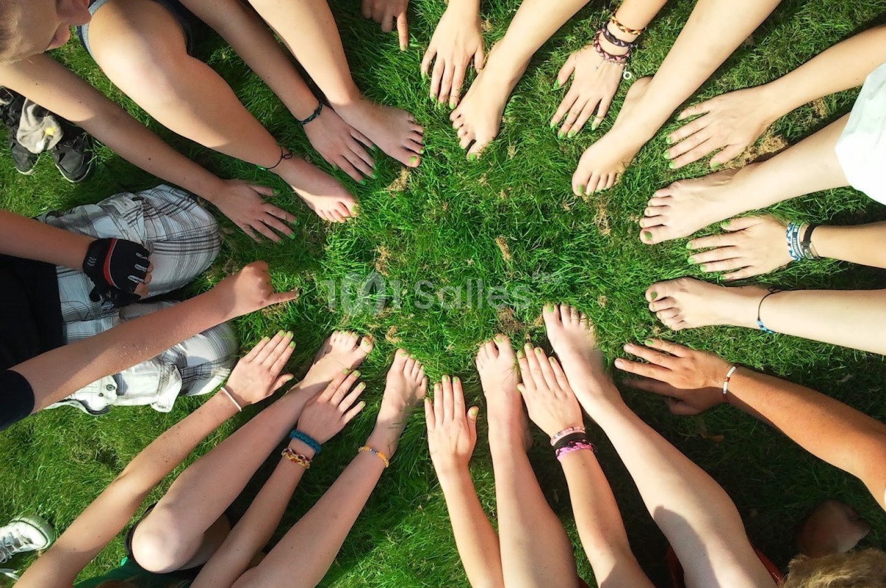 Des mains et pieds nus disposés en cercle sur de l'herbe verte.