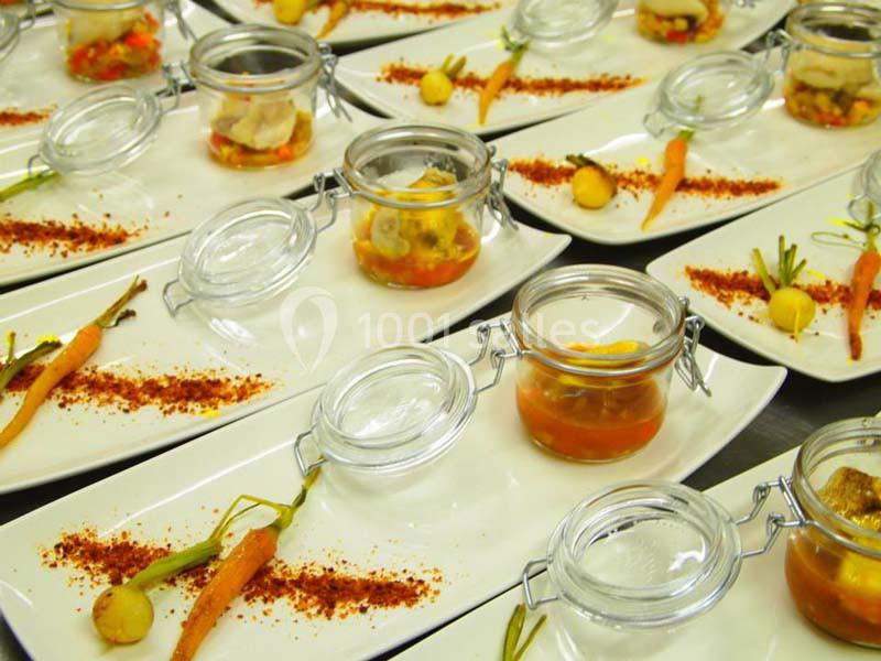 Assiettes dressées avec des bocaux de légumes marinés, carottes miniatures et poudre d'épices en décoration.