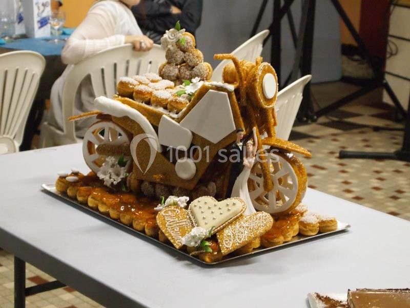 Pièce montée en forme de moto, composée de choux et nougatine, présentée sur une table dans une salle.
