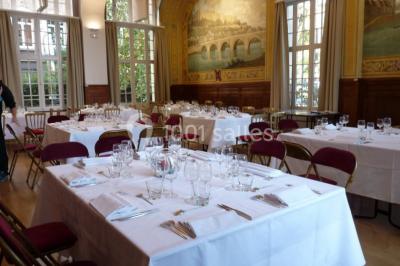 Banc en pierre au premier plan dans une allée bordée d'arbres, avec des promeneurs visibles au loin.
