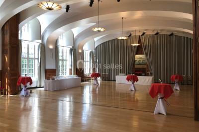 Banc en pierre au premier plan dans une allée bordée d'arbres, avec des promeneurs visibles au loin.