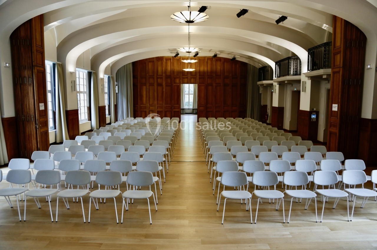 Location salle Paris 14 (Paris) - Cité Universitaire – Fondation Biermans-Lapôtre #22 Salle de conférence lumineuse avec rangées de chaises blanches alignées sur un sol en bois clair.