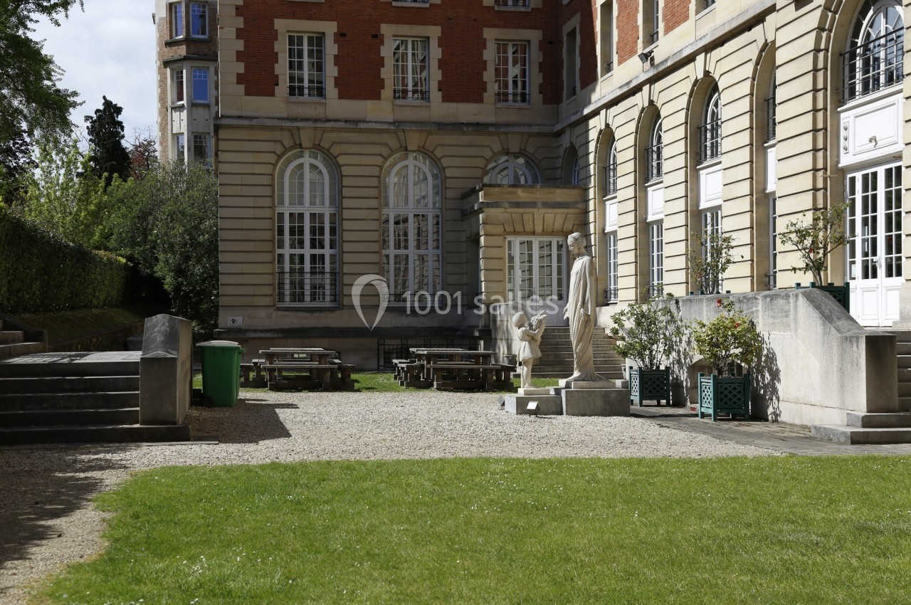 Location salle Paris 14 (Paris) - Cité Universitaire – Fondation Biermans-Lapôtre #27 Cour intérieure avec pelouse, tables de pique-nique, statues et façade en briques et pierre avec grandes fenêtres.