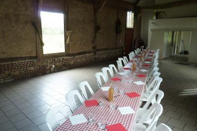 Salle rustique avec murs en pierre et poutres apparentes, aménagée avec tables hautes, canapés et décorations simples.