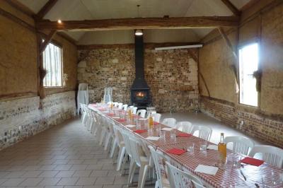Salle rustique avec murs en pierre et poutres apparentes, aménagée avec tables hautes, canapés et décorations simples.