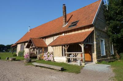 Salle rustique avec murs en pierre et poutres apparentes, aménagée avec tables hautes, canapés et décorations simples.