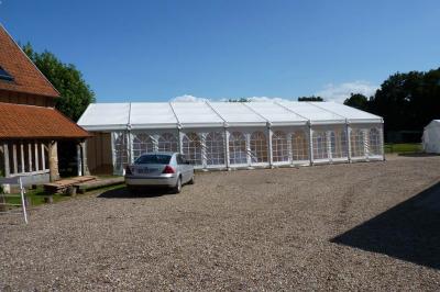 Salle rustique avec murs en pierre et poutres apparentes, aménagée avec tables hautes, canapés et décorations simples.