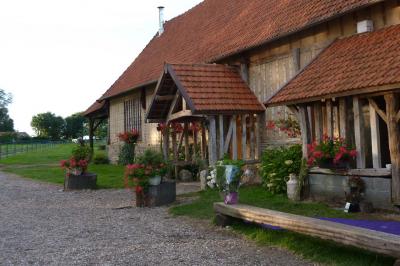 Salle rustique avec murs en pierre et poutres apparentes, aménagée avec tables hautes, canapés et décorations simples.