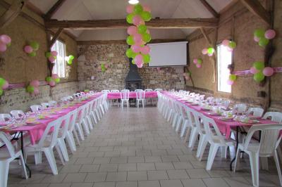Salle rustique avec murs en pierre et poutres apparentes, aménagée avec tables hautes, canapés et décorations simples.