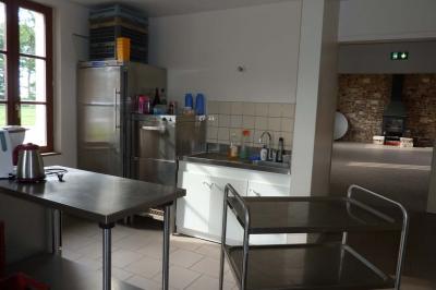 Salle rustique avec murs en pierre et poutres apparentes, aménagée avec tables hautes, canapés et décorations simples.