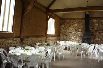 Salle rustique avec murs en pierre et poutres apparentes, aménagée avec tables hautes, canapés et décorations simples.