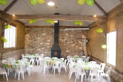 Salle rustique avec murs en pierre et poutres apparentes, aménagée avec tables hautes, canapés et décorations simples.