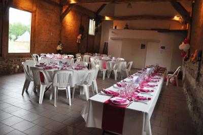Salle rustique avec murs en pierre et poutres apparentes, aménagée avec tables hautes, canapés et décorations simples.