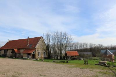 Salle rustique avec murs en pierre et poutres apparentes, aménagée avec tables hautes, canapés et décorations simples.