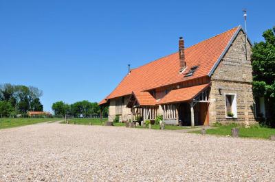 Salle rustique avec murs en pierre et poutres apparentes, aménagée avec tables hautes, canapés et décorations simples.