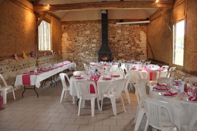 Salle rustique avec murs en pierre et poutres apparentes, aménagée avec tables hautes, canapés et décorations simples.