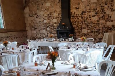 Salle rustique avec murs en pierre et poutres apparentes, aménagée avec tables hautes, canapés et décorations simples.
