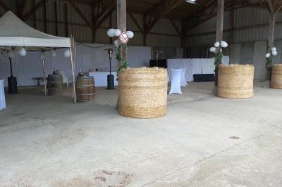 Salle rustique avec murs en pierre et poutres apparentes, aménagée avec tables hautes, canapés et décorations simples.