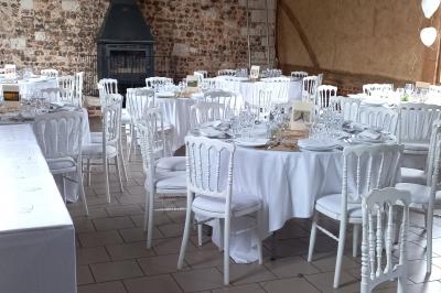 Salle rustique avec murs en pierre et poutres apparentes, aménagée avec tables hautes, canapés et décorations simples.