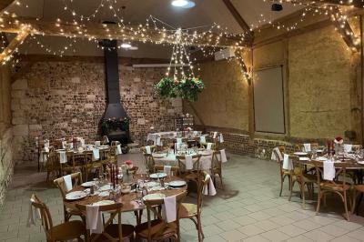 Salle rustique avec murs en pierre et poutres apparentes, aménagée avec tables hautes, canapés et décorations simples.