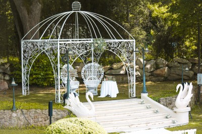 Cérémonie de mariage en plein air avec des invités assis, un couple avançant vers une arche décorée.