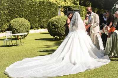 Cérémonie de mariage en plein air avec des invités assis, un couple avançant vers une arche décorée.
