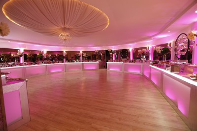 Des personnes discutent et se promènent le long d'une balustrade en fer forgé bordée de végétation, sous des arbres.