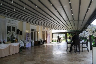 Des personnes discutent et se promènent le long d'une balustrade en fer forgé bordée de végétation, sous des arbres.