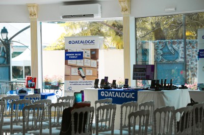 Miniature Location salle Le Coudray-Montceaux (Essonne) - Le Manoir des Cygnes #11 Salle lumineuse avec des stands promotionnels, des affiches et des tables recouvertes de nappes bleues, entourées de chaises…